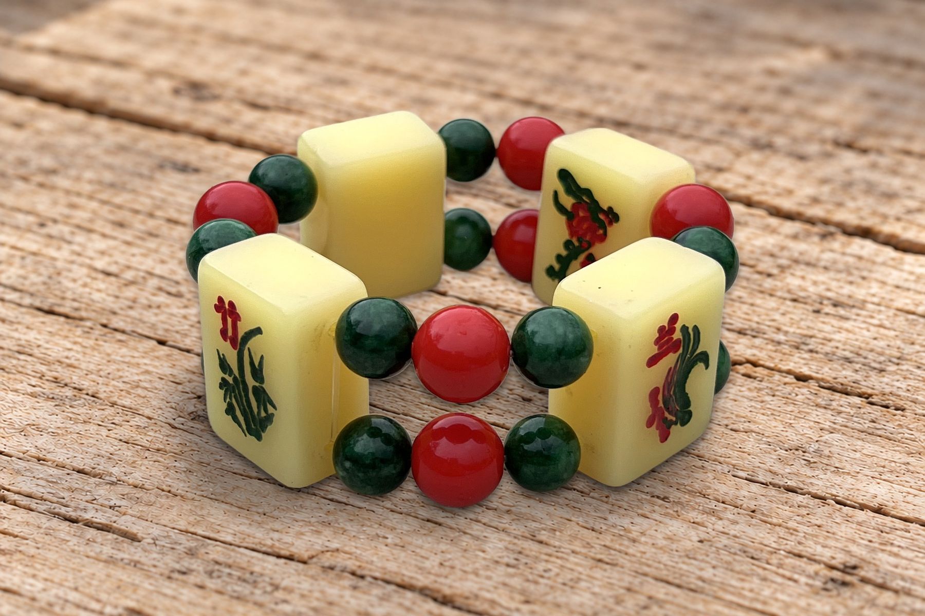 Bracelet en tuiles de mahjong anciennes, perles rouges et vertes, posé sur une planche de vieux bois